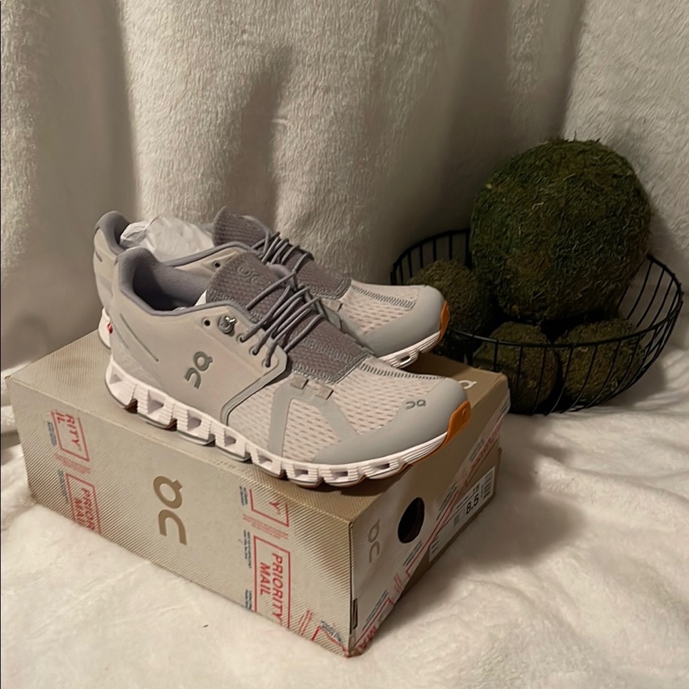 On Running Cloud Sneakers - Gray and White with orange on bottom.